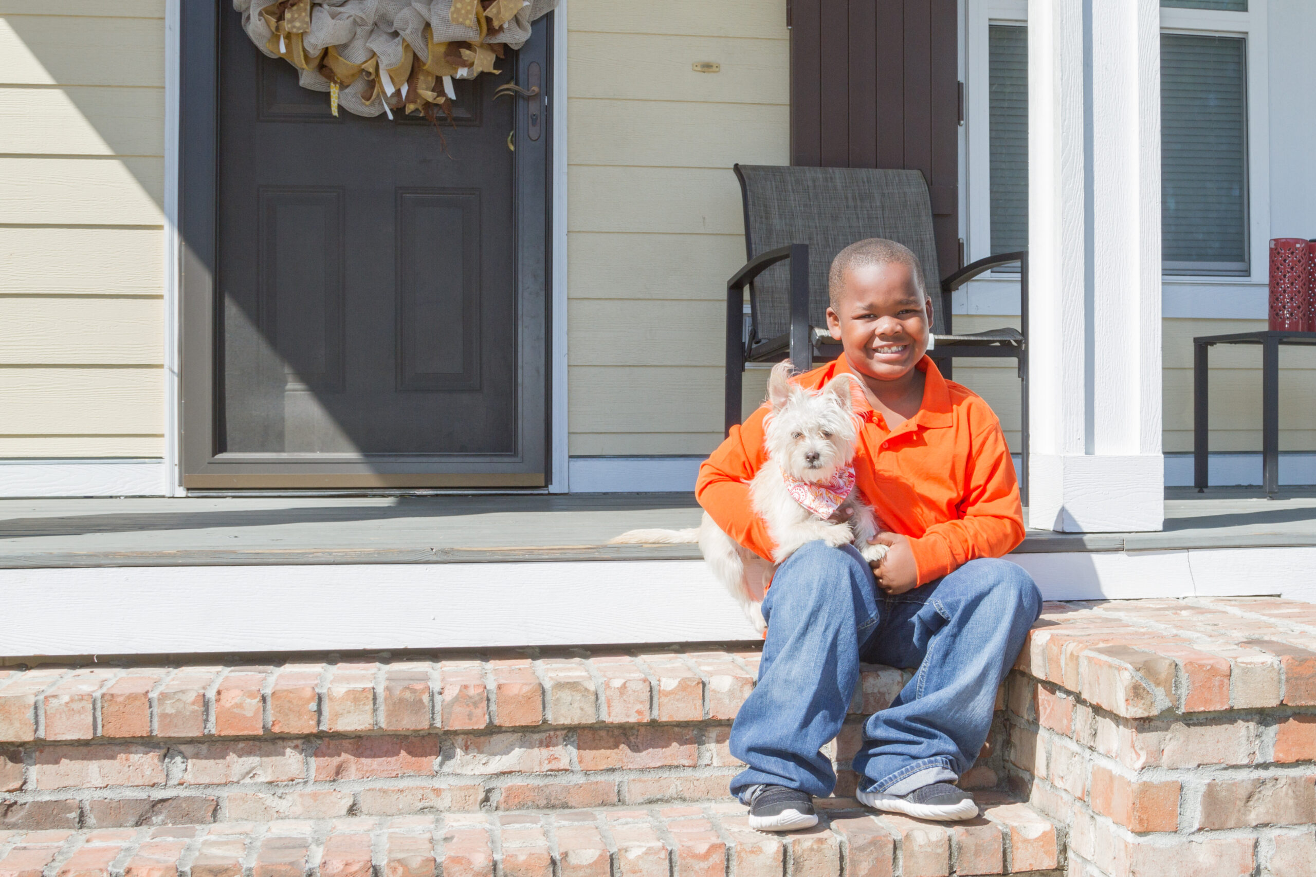 child sitting with dog on steps to porch